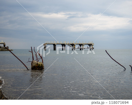 Reinforced concrete sticking out of the water. Remains of an old bridge in the sea. Ruined pier. Abandoned. Armature at sea. 118071694