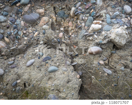 Layers of earth on a beach made of pebbles. Soil cut. Cobblestones and earth. After the excavator. 118071707