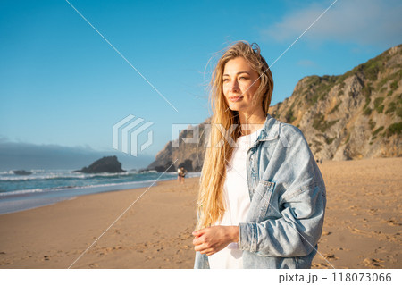 Blond woman looking away while standing on sandy Blond woman looking away while standing on sandy 118073066