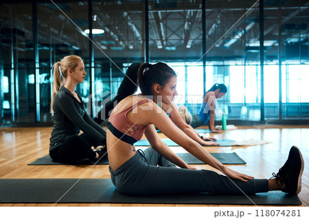 Getting ready for yoga. Shot of a group of attractive young women stretching before their yoga class begins. Getting ready for yoga. Shot of a group of attractive young women stretching before their yoga class begins. 118074281