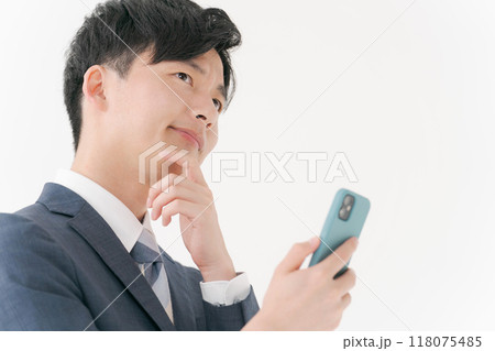 スマホを見て悩むビジネスマン スマホを見て悩むビジネスマン 118075485