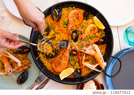 Womens hands lay out sea paella in plates for family dinner 118077812