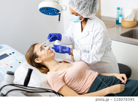 Woman cosmetician giving face injections of botulinum toxin for young woman 118078395