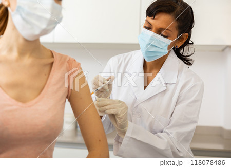 Doctor injecting shot of vaccine to woman Doctor injecting shot of vaccine to woman 118078486