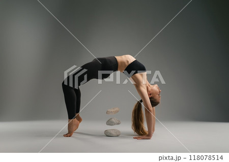 A flexible individual performs a yoga pose with stones in the background A flexible individual performs a yoga pose with stones in the background 118078514