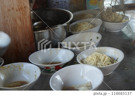Tukang Mie Ayam or a noodle vendor preparing servings of chicken noodle soup. Tukang Mie Ayam or a noodle vendor preparing servings of chicken noodle soup. 118083137