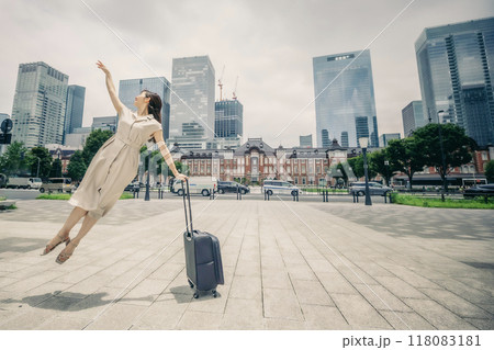 キャリーバッグをひいて旅にでた、若い女性の心弾む様子 118083181