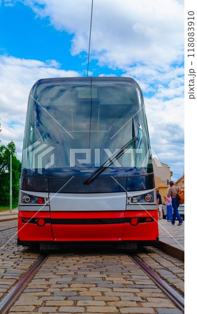 Front view of a modern red and white tram on a brick track in a bustling urban city environment Front view of a modern red and white tram on a brick track in a bustling urban city environment 118083910