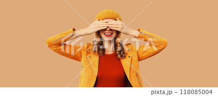 Stylish surprised young woman covering her eyes with hands, fashionable girl in orange hat, jacket Stylish surprised young woman covering her eyes with hands, fashionable girl in orange hat, jacket 118085004