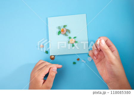 Shell and paper craft turtle on blue background evokes summer feeling with minimalism and sea like vibe. Simple yet elegant design highlights natural beauty and artistic craftsmanship. DIY, top view, 118085380