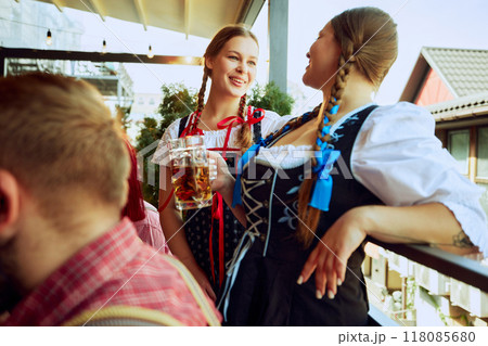 Two beautiful young women in traditional Bavarian clothes, waitress standing at bar, cheerfully talking. 118085680