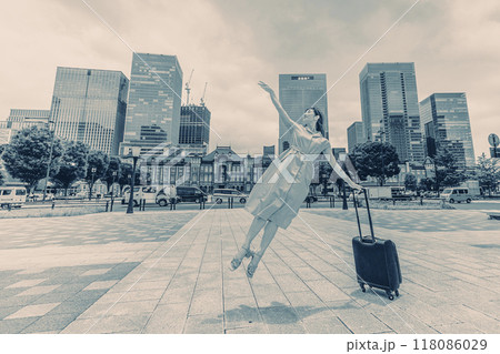 キャリーバッグをひいて旅にでた、若い女性の心弾む様子 キャリーバッグをひいて旅にでた、若い女性の心弾む様子 118086029