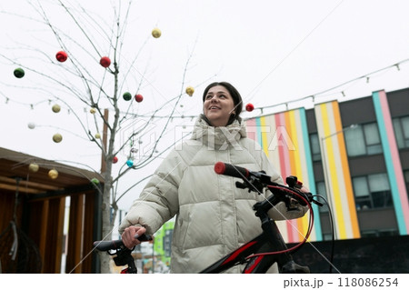 Woman in White Coat Holding Bicycle 118086254