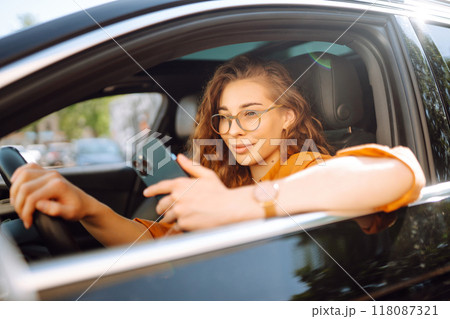 Beautiful woman driver in a car with a phone in her hands. Leisure, travel, technology, navigation. Beautiful woman driver in a car with a phone in her hands. Leisure, travel, technology, navigation. 118087321