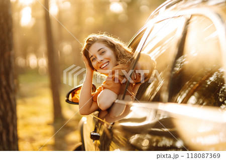 Happy woman on summer trip, travels leaning out of the car window. Active lifestyle. Travel concept. Happy woman on summer trip, travels leaning out of the car window. Active lifestyle. Travel concept. 118087369