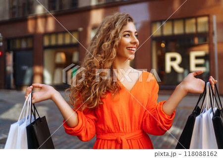Happy woman with shopping bags walking on sunny street. Concept of lifestyle, buying, selling. Happy woman with shopping bags walking on sunny street. Concept of lifestyle, buying, selling. 118088162