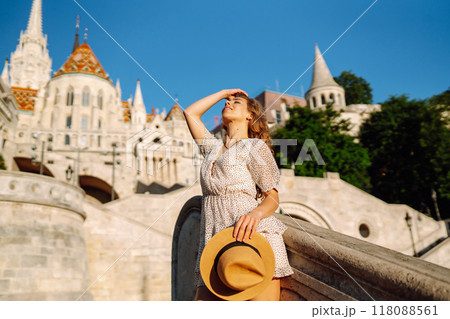 Happy young woman in hat at dawn enjoys view of beautiful buildings. Lifestyle, tourism concept. 118088561
