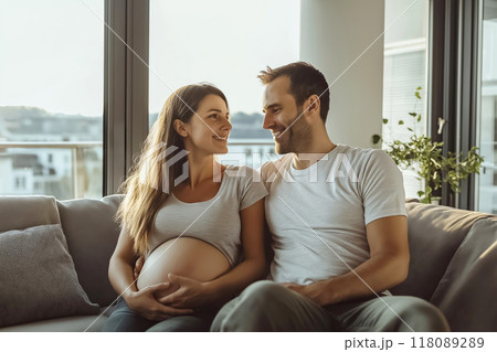 Happy pregnant couple relaxing on sofa at home Happy pregnant couple relaxing on sofa at home 118089289