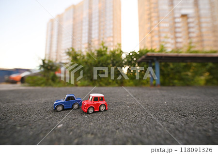 two toy cars against the backdrop of a multi-storey new building and greenery. Real estate, residential complex, new, parking.Real estate, residential complex, new, parking. 118091326
