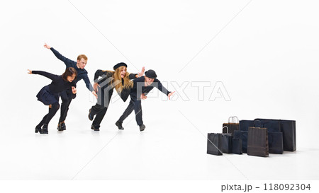 Group of people all in black outfits showing readiness to run, racing towards a pile of tempting black shopping bags, ready to grab their haul. 118092304