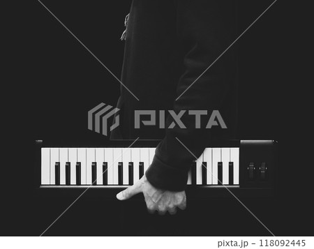 BW male musician holding music keyboard, isolated on black. music background 118092445