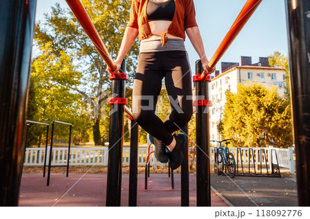 Bottom view of woman push-ups from sports horizontal bar. Concept of sports and outdoor training 118092776
