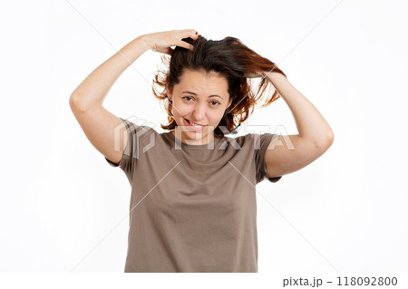 Woman holds her hands to her hair with concern. White background. The concept of hair care 118092800