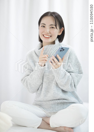 スマホを使用するセーターを着た若い女性 118094580