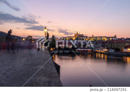 A twilight view of Prague Castle from Charles Bridge, with sunset colors reflecting on the calm Vltava River. Silhouetted towers rise against the glowing sky, creating a serene, romantic atmosphere. A twilight view of Prague Castle from Charles Bridge, with sunset colors reflecting on the calm Vltava River. Silhouetted towers rise against the glowing sky, creating a serene, romantic atmosphere. 118097291