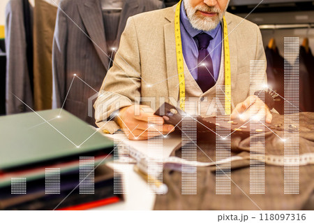 A man is sitting at a desk with a stack of papers and a cell phone 118097316