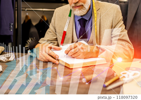 A man is writing in a notebook while looking at a graph 118097320