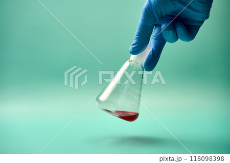 Hand shaking an Erlenmeyer flask with a red chemical. Hand shaking an Erlenmeyer flask with a red chemical. 118098398