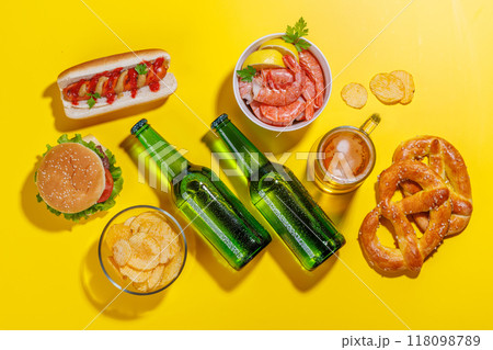 A vibrant photo showcasing bottles of beer surrounded by various snacks and fast food 118098789