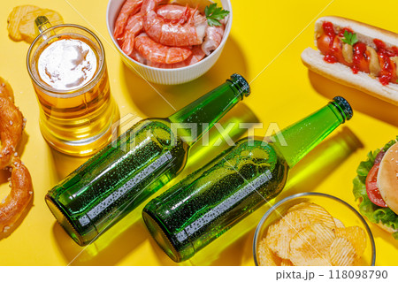 A vibrant photo showcasing bottles of beer surrounded by various snacks and fast food A vibrant photo showcasing bottles of beer surrounded by various snacks and fast food 118098790