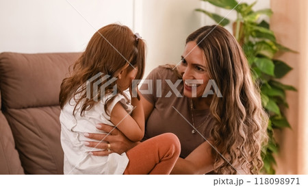 Cheerful woman and daughter playing peek a boo at home 118098971