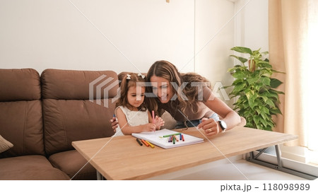 Caring mother and daughter drawing in book at apartment Caring mother and daughter drawing in book at apartment 118098989