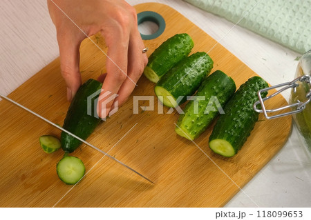 Woman hands cutting ends of cucumbers to cook pickles on kitchen, top view. 118099653