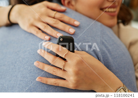 Close up on smart key in hand of happy female owner embracing boyfriend after successful car buying at dealership center, copy space 118100241