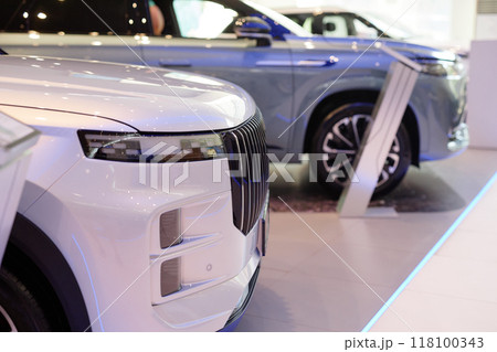 Side view of white car bumper with xenon headlights and brutal radiator grille displayed in showroom at dealership center, copy space Side view of white car bumper with xenon headlights and brutal radiator grille displayed in showroom at dealership center, copy space 118100343