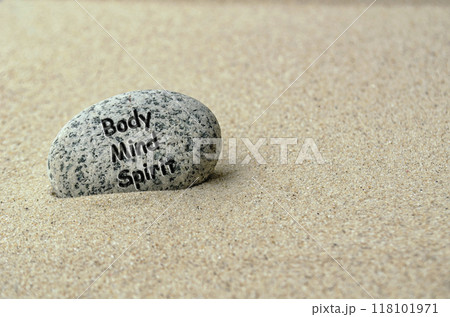 Body, Mind and Spirit text on zen stone buried in the sand. 118101971