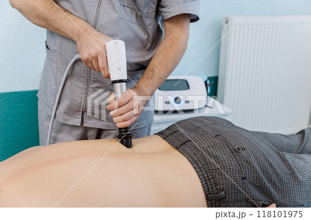 Shockwave therapy session for back pain relief in a clinical setting with a professional therapist Shockwave therapy session for back pain relief in a clinical setting with a professional therapist 118101975