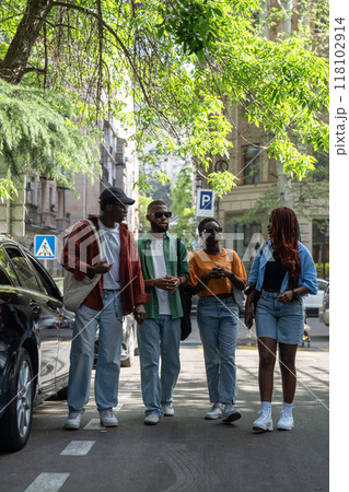 Friendly company of thoughtful black friends students buddies walking outside along town streets. 118102914