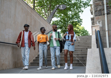 Group of thoughtful African American friends enthusiastically discuss various topics, walk outdoors 118102973
