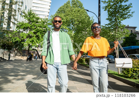 Happy lovers couple of African American students walking together, holding hands, laughing merrily. 118103266