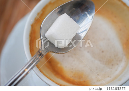 A delightful cup of aromatic espresso with a sugar cube placed on a spoon above it for sweetness A delightful cup of aromatic espresso with a sugar cube placed on a spoon above it for sweetness 118105275