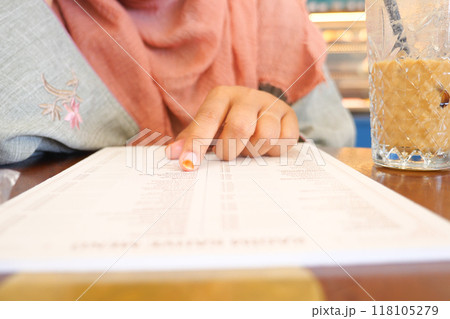 women hand reading a food menu at cafe. women hand reading a food menu at cafe. 118105279