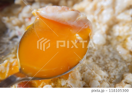 CloseUp of a Spoon with a Runny Egg Yolk on Fried Egg Whites, a tasty and healthy breakfast 118105300