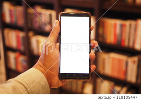 holding smart phone with empty screen against library background holding smart phone with empty screen against library background 118105447