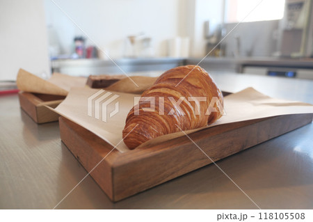 A Freshly Baked Croissant Resting on a Wooden Board in a Beautiful Modern Kitchen Space A Freshly Baked Croissant Resting on a Wooden Board in a Beautiful Modern Kitchen Space 118105508