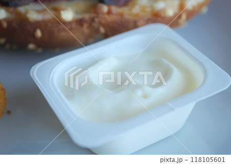 A Creamy White Sauce in a Plastic Container is Positioned Next to Delicious Food Items 118105601